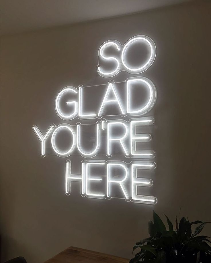 neon sign saying "so glad you're here"